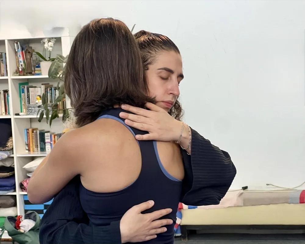 שתי משתתפות בחיבוק, רגע של קרבה ושחרור